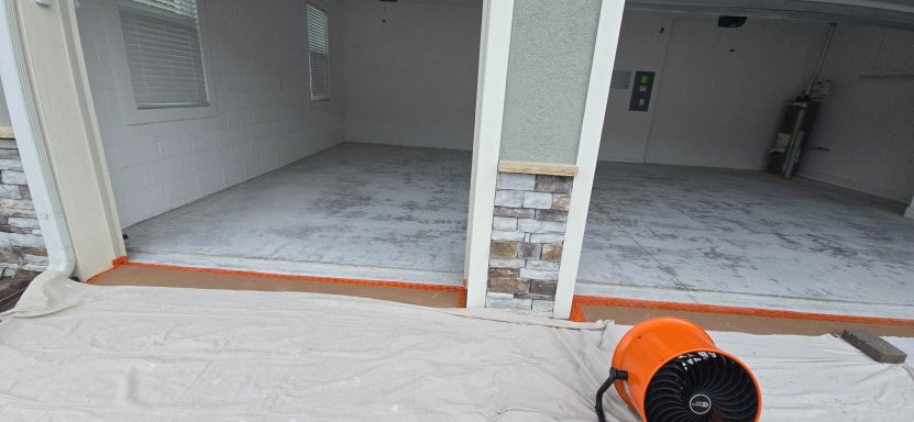 Empty garage space with a clean concrete floor and an orange fan.