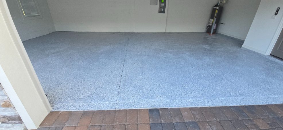 Empty garage with a concrete floor and a door leading outside.